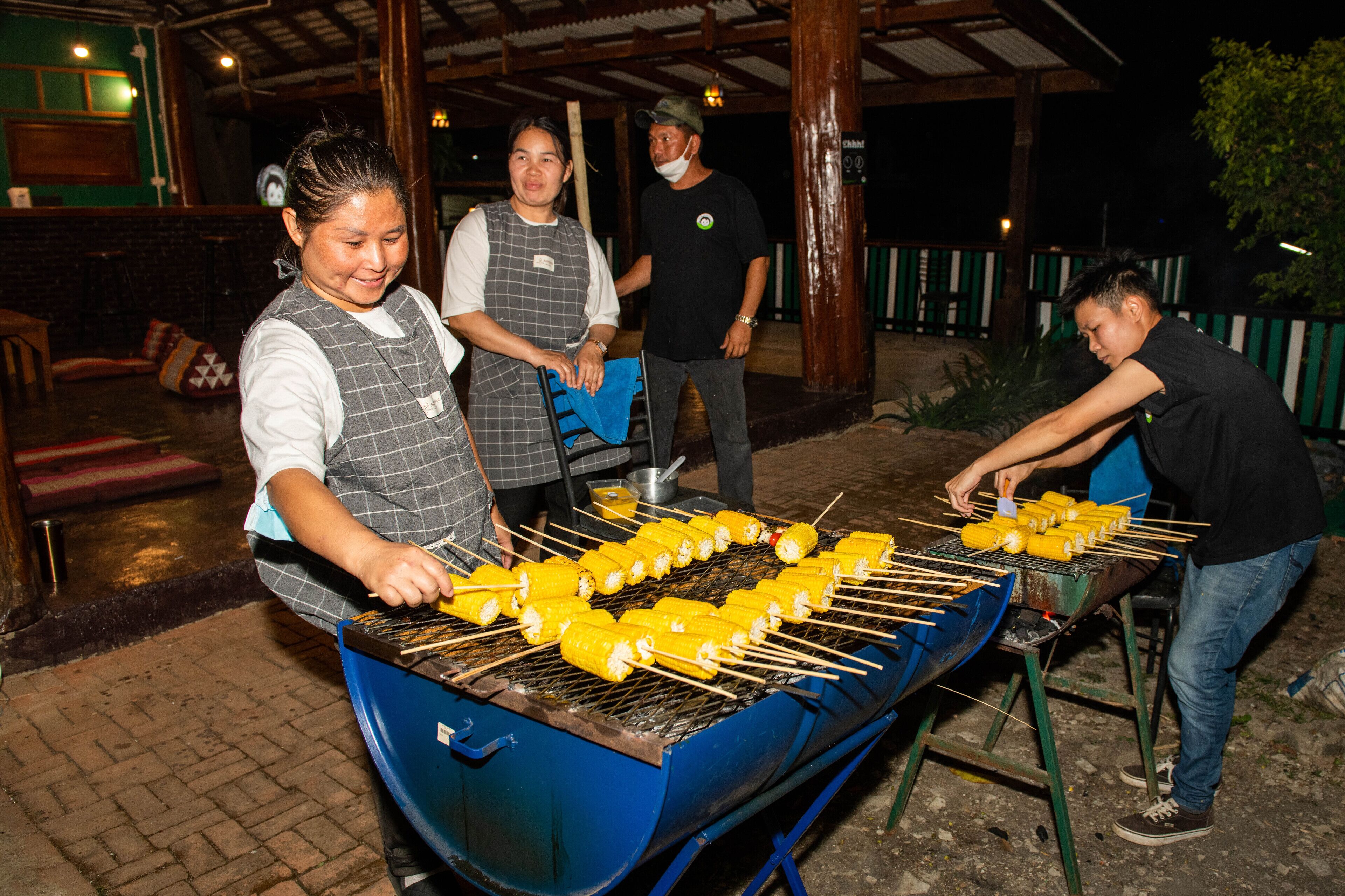 A grill with corn on the cob being cooked outdoors.