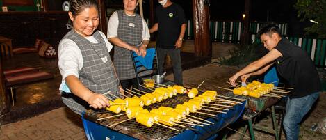 A grill with corn on the cob being cooked outdoors.