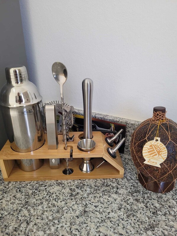 A kitchen counter with a wooden stand holding various kitchen tools, including a blender, a spoon, and a bottle opener.