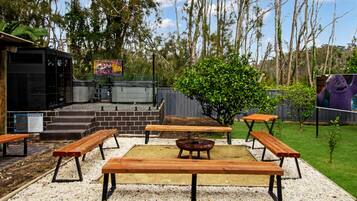 An outdoor patio area with wooden benches and a barbecue grill.