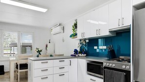 A modern kitchen with white cabinets, a stainless steel stove, and a blue backsplash.