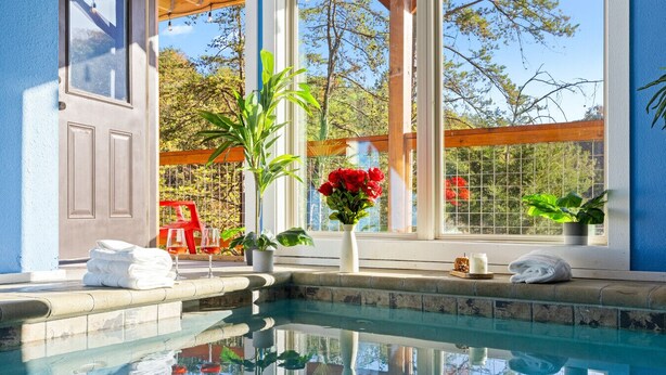 A pool area with a clear view of the surrounding landscape, a wooden deck, and a glass enclosure with a view of trees. - Heavenly Bliss By Ghosal Luxury Lodging (Sevierville)