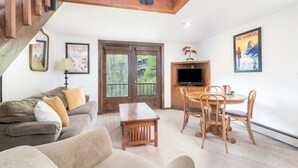 A living room with a sofa, a wooden table, and a TV. - Manitou Lodge 7 Hotel Room by Alpine Lodging Telluride (Telluride)