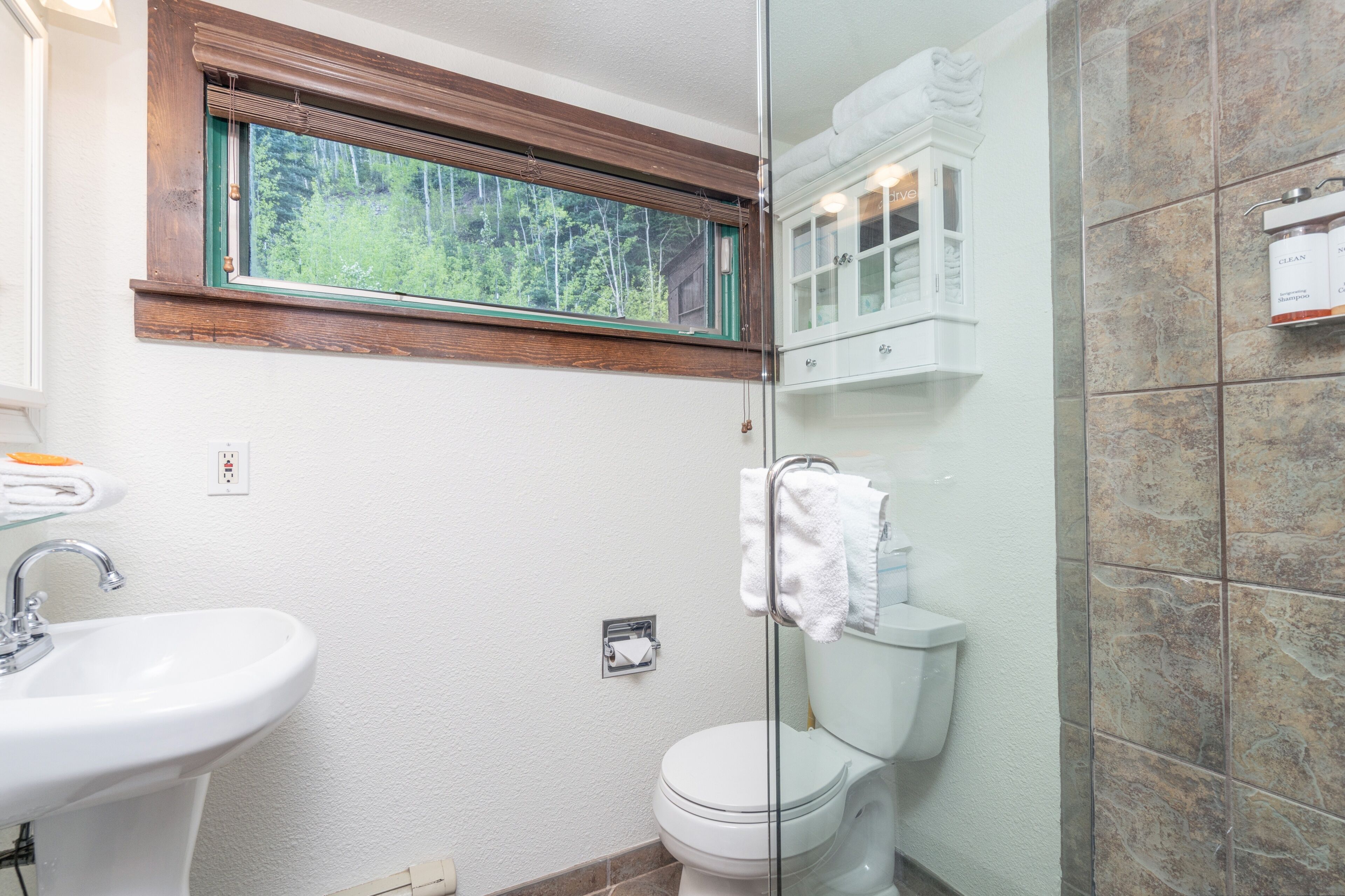 Baño con lavamanos, inodoro y zona de ducha.