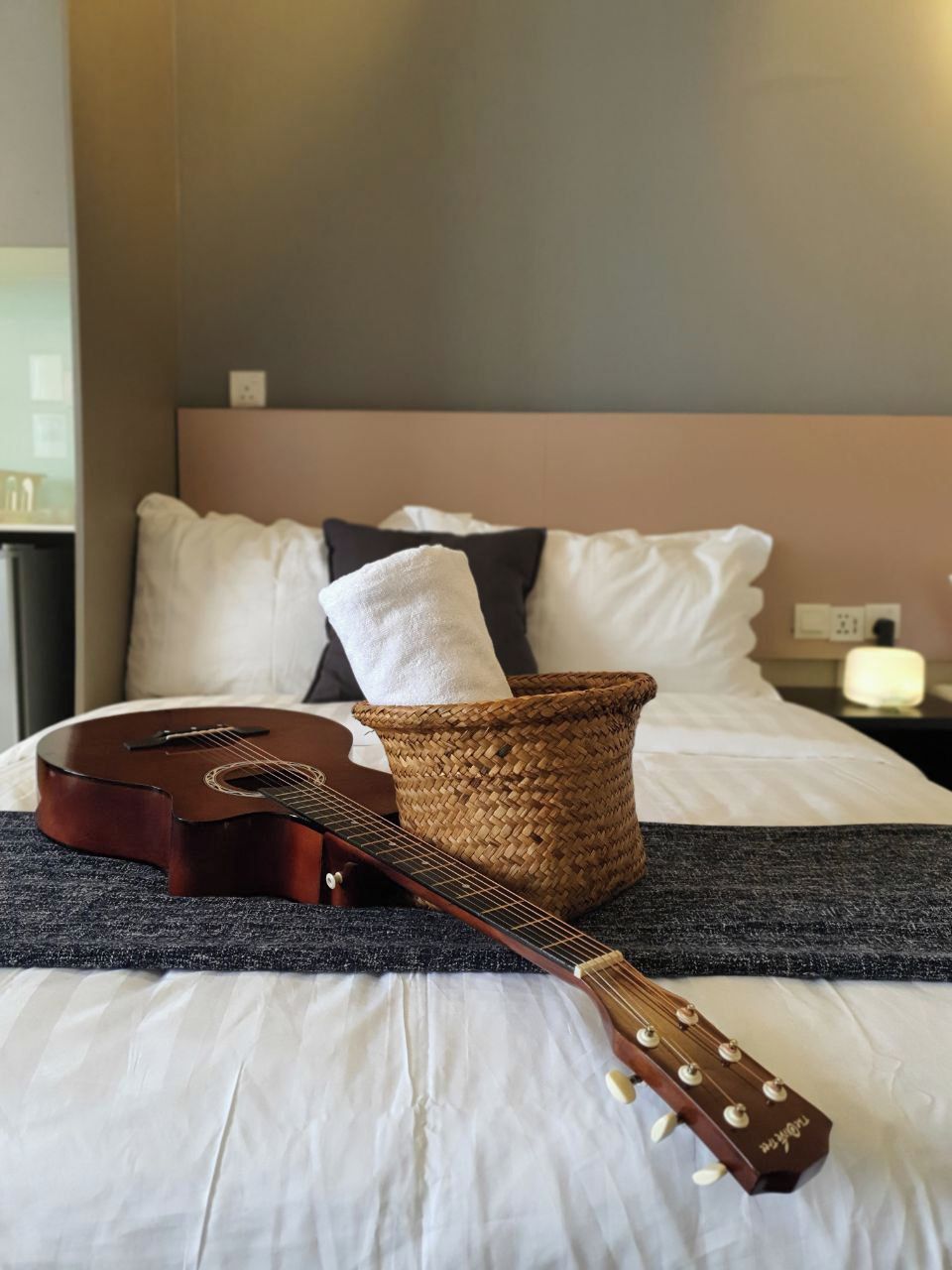 Un llit amb una guitarra, una cistella teixida i una almoçada.