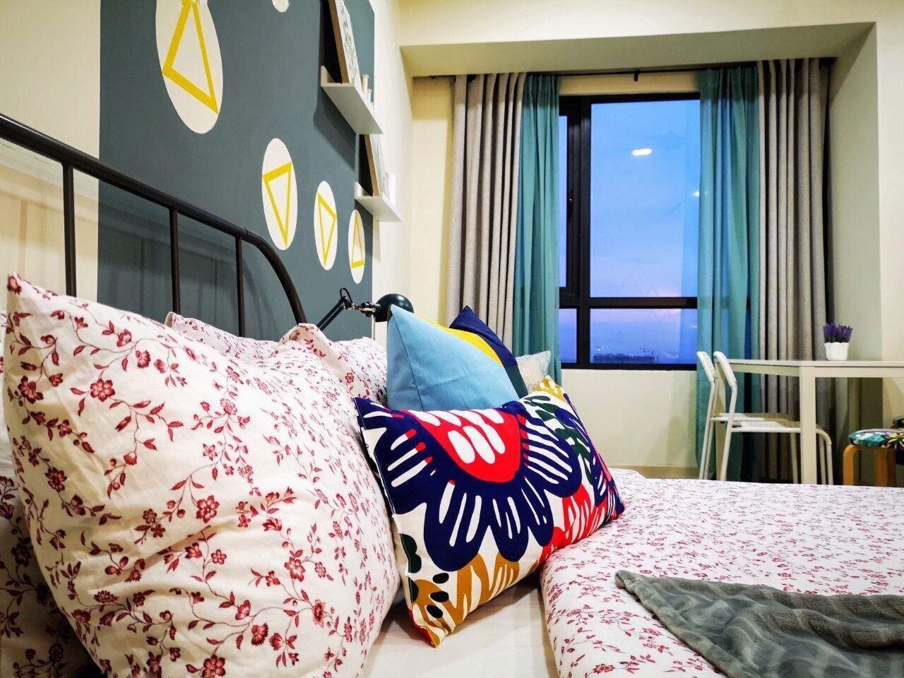 A hotel room with a bed, a desk, and a window with curtains.