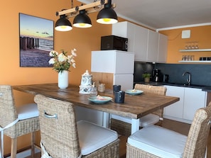 Una cucina moderna con un tavolo da pranzo in legno, sedie in vimini e un frigorifero bianco.