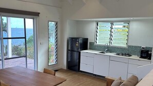 Una cocina moderna con armarios blancos, un refrigerador negro y un ventanal con persianas.