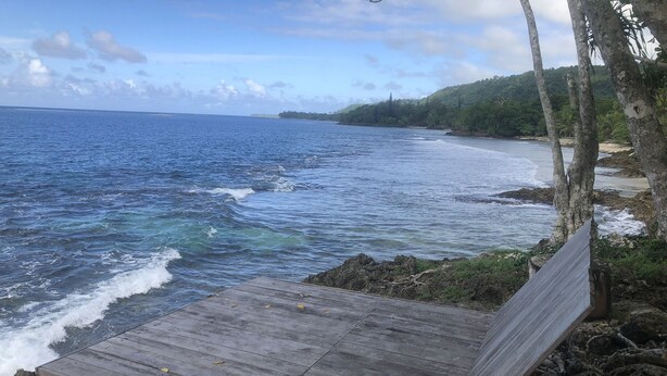 Un banco de madera con vista a una playa donde las olas rompen en la orilla.