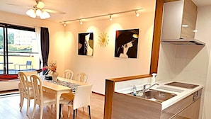 A modern kitchen with a built-in stove, a sink, and a dining area with a table and chairs. - Alloggio Nanki Shirahama (Shirahama)
