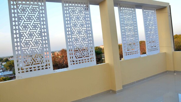 A balcony with white lattice panels and a view of the cityscape. - Hotel Ranthambhore Uday (Sawai Madhopur)