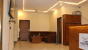 A hotel lobby with a brown sofa, a wooden cabinet, and a sign indicating the hotel name. - Hotel Ranthambhore Uday (Sawai Madhopur)