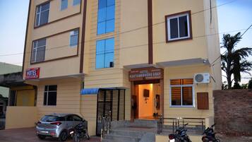 A hotel with a signboard, a staircase leading to the entrance, and parked motorcycles.
