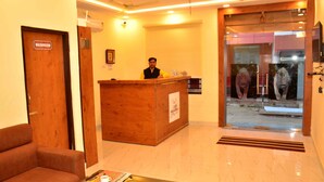 A reception desk with a wooden finish, a sign indicating a washroom, and a framed picture on the wall. - Hotel Ranthambhore Uday (Sawai Madhopur)