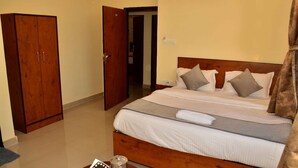 A hotel room with a wooden bed, a wardrobe, and a bathroom visible through an open door. - Hotel Ranthambhore Uday (Sawai Madhopur)