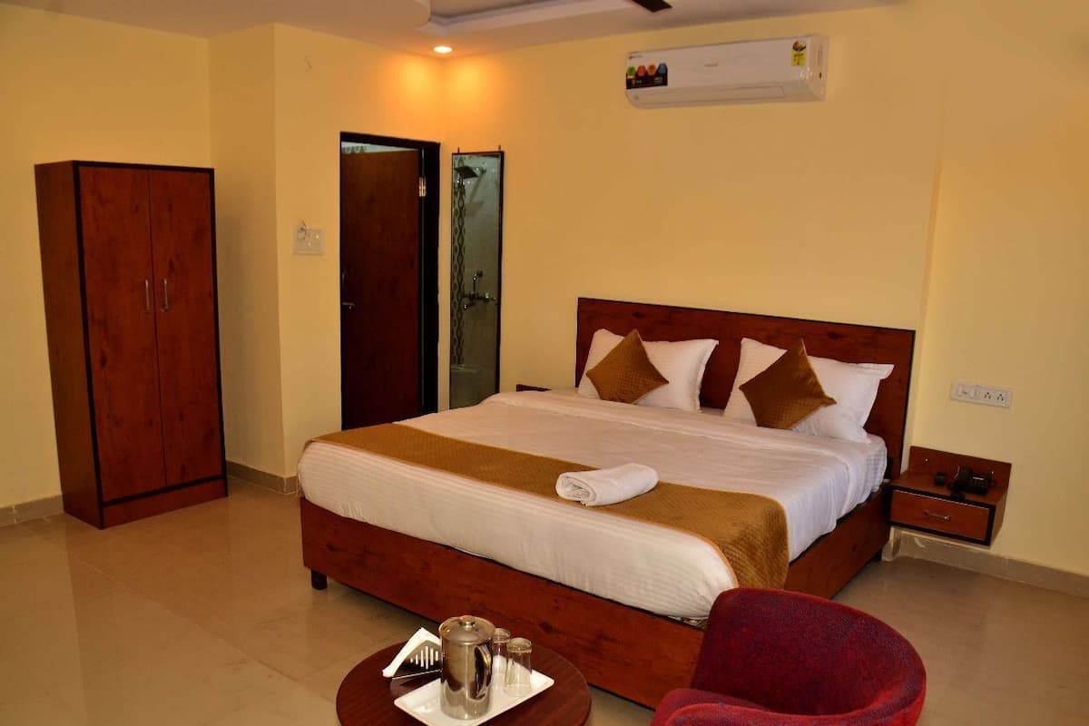 A hotel room with a large bed, a wardrobe, a shower area, and a small table with a tray of breakfast items.