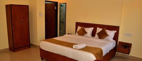 A hotel room with a large bed, a wardrobe, a shower area, and a small table with a tray of breakfast items.