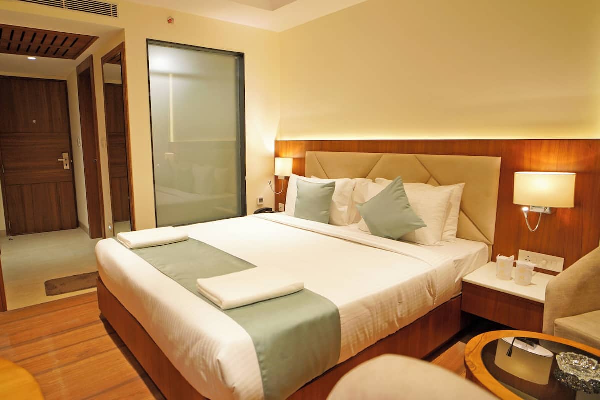 A hotel room with a large bed, wooden furniture, a desk, and a chair.