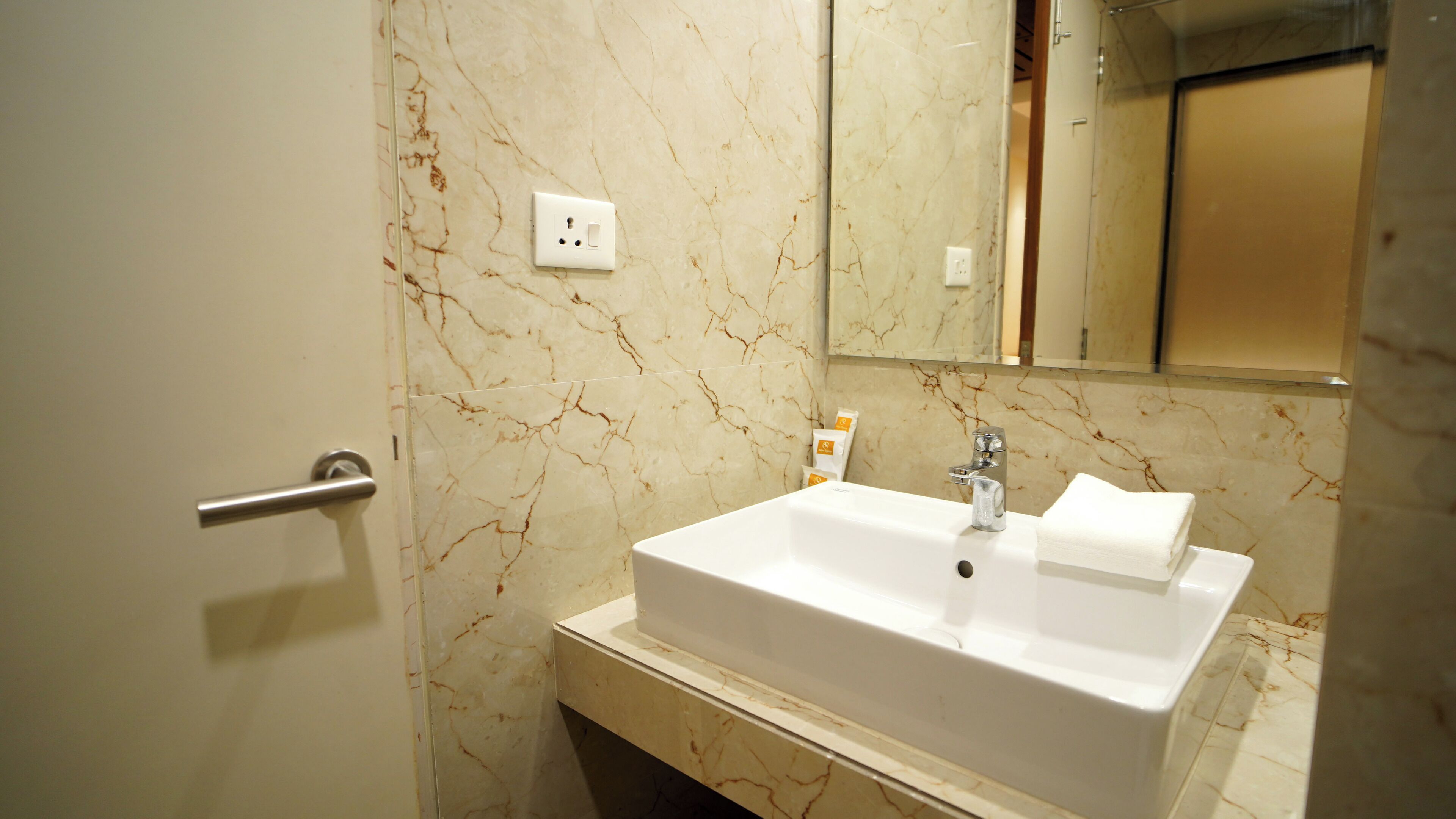 A bathroom with a marble sink, a mirror, and a towel.