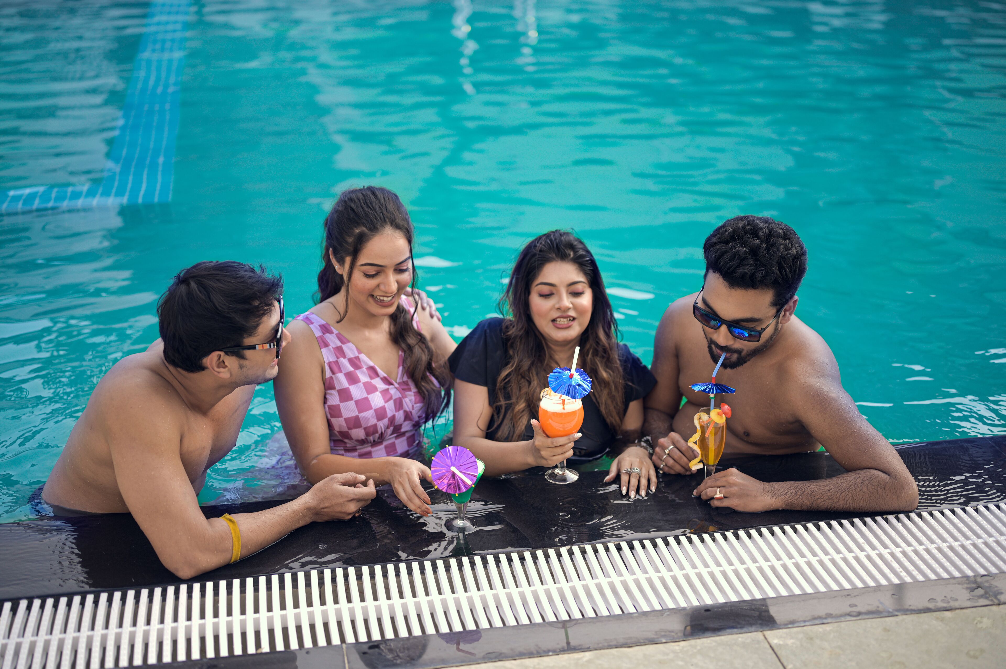 A group of people sitting by a poolside with drinks.