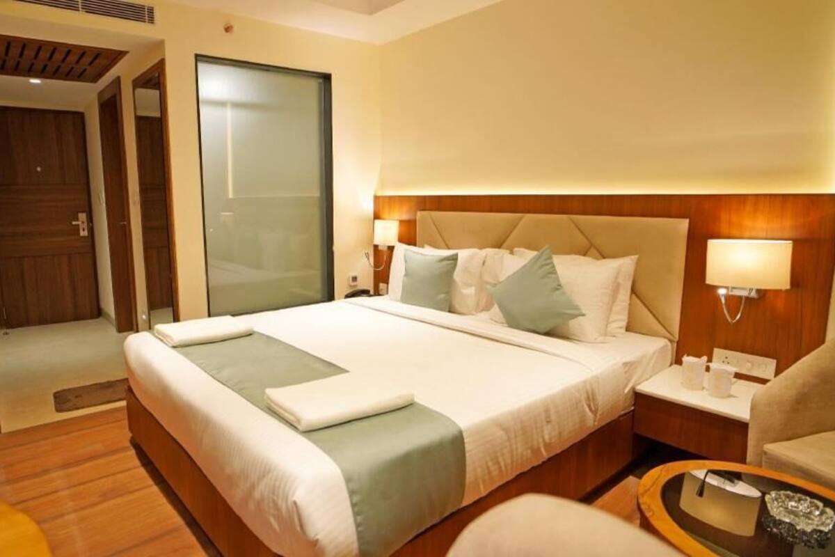 A hotel room with a large bed, bedside tables, a chair, and a small table.