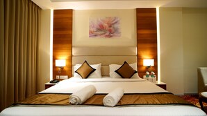 Habitación de hotel con una cama grande, dos lámparas de noche, un cuadro en la pared y una silla en la esquina.