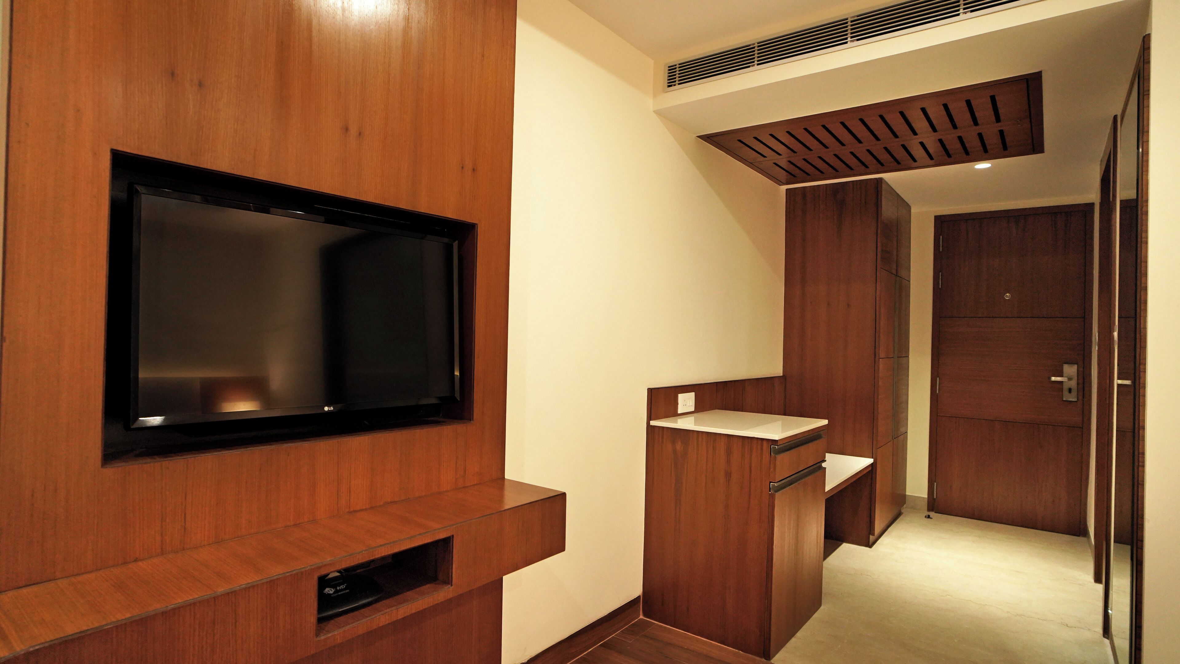 A modern bathroom with a wooden vanity, a mirror, and a built-in television.