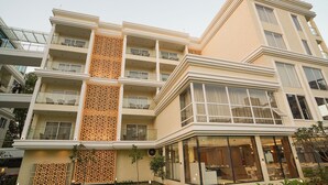 Un hotel de varios pisos con balcones, un panel decorativo central y un comedor con paredes de vidrio.