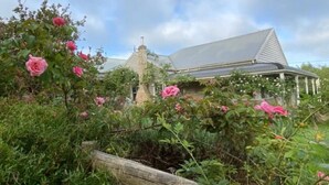 Una casa amb un jardí gran, una xemeneia destacada i un porxo cobert.