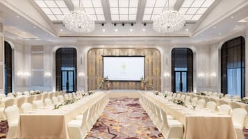 A conference room with a long table set for a meeting, large windows, and a chandelier.