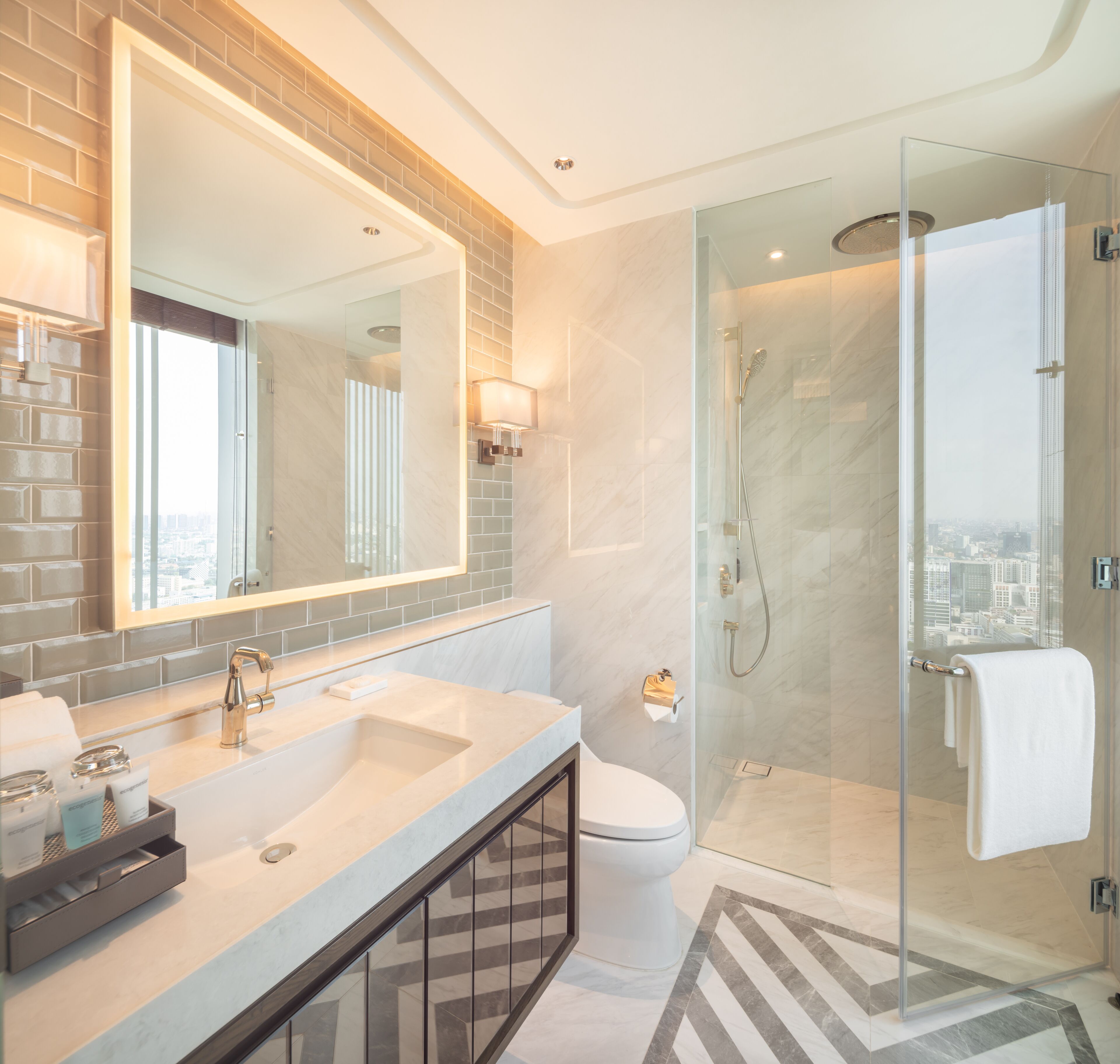 A modern bathroom with a glass-enclosed shower, a large mirror, and a dual sink vanity.