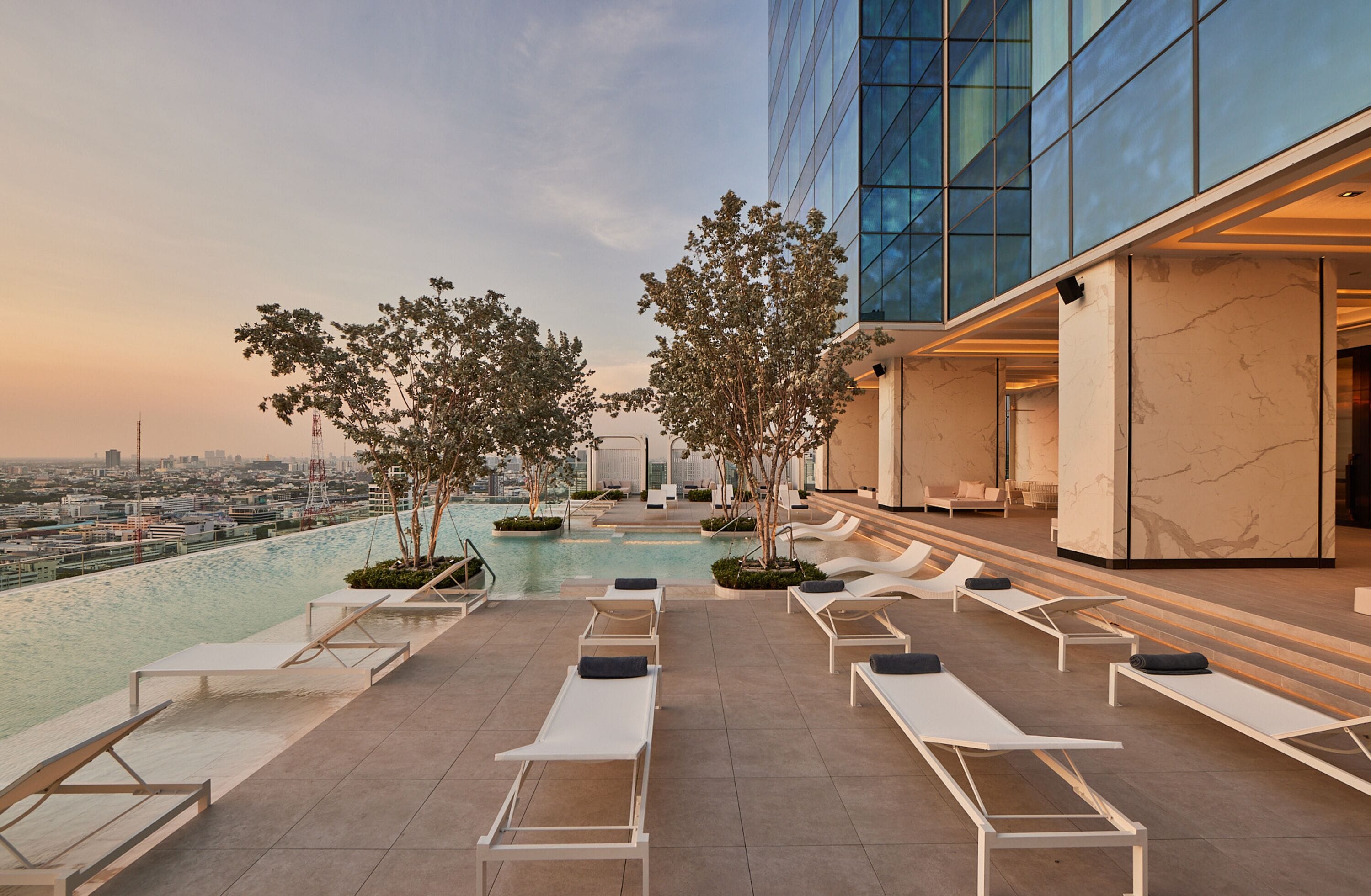 A rooftop pool area with lounge chairs and a view of the city skyline.