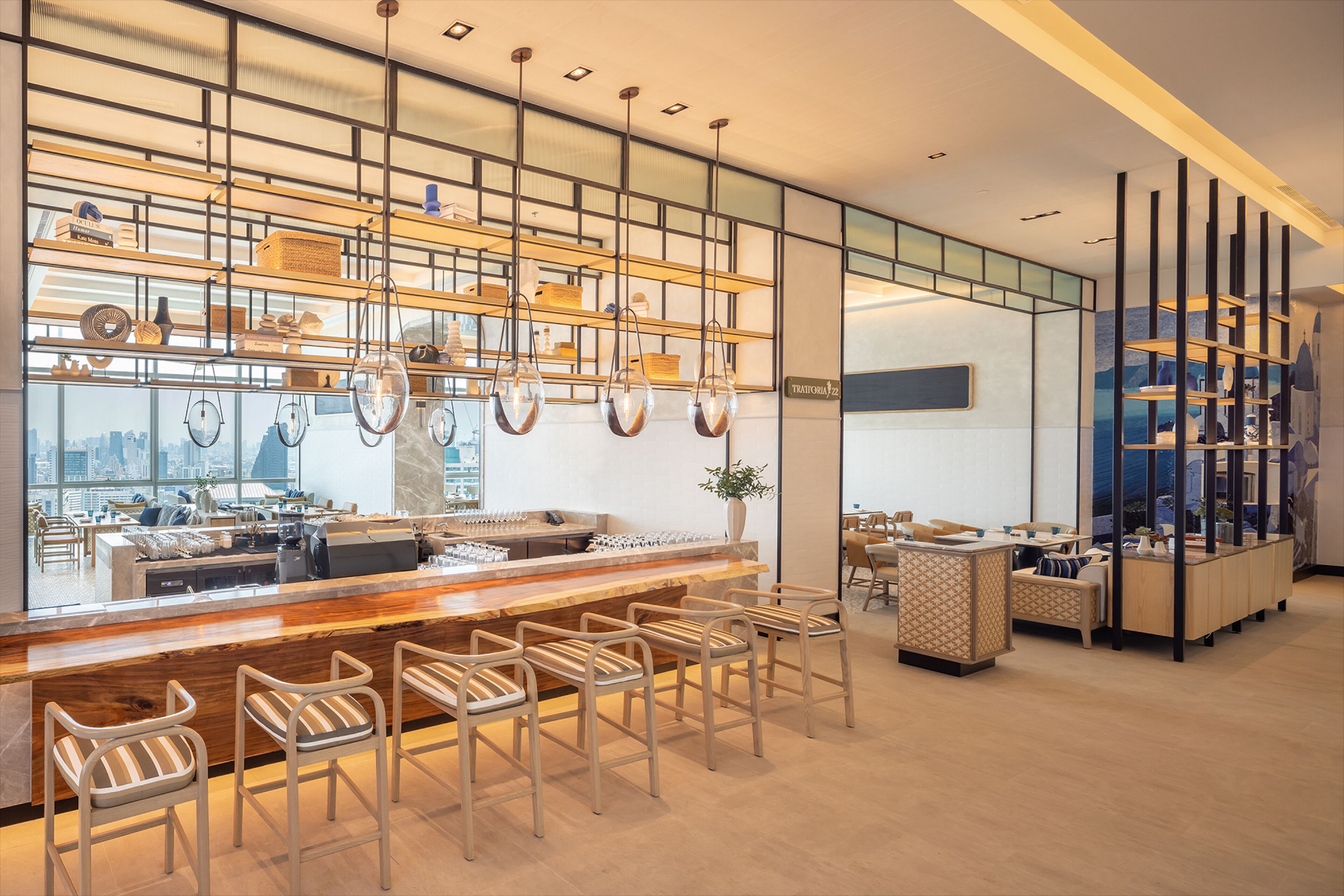 A modern bar area with a wooden counter, metal chairs, and a city view through large windows.