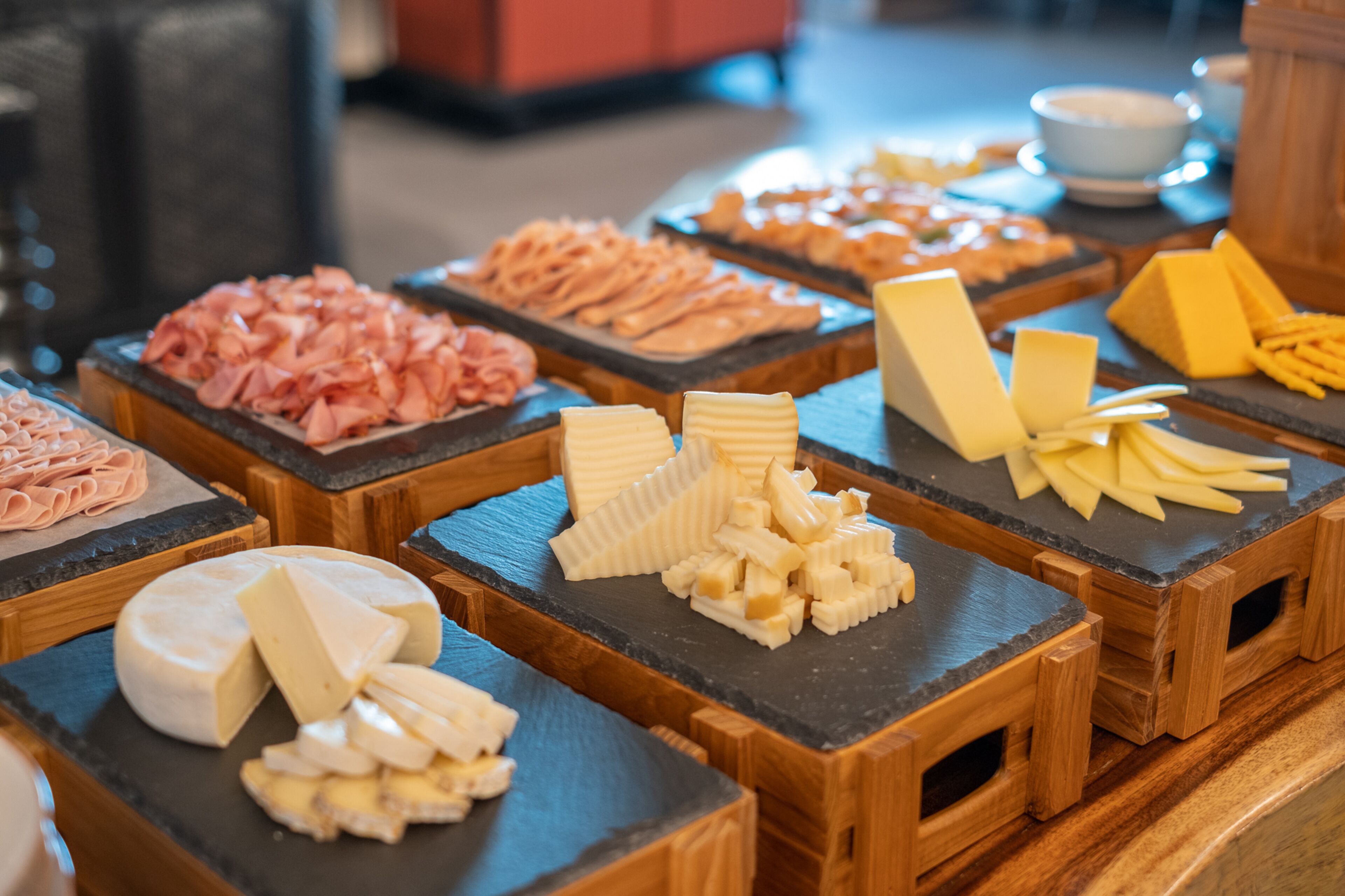 A cheese and meat buffet with various types of cheese and sliced meats displayed on wooden boards.
