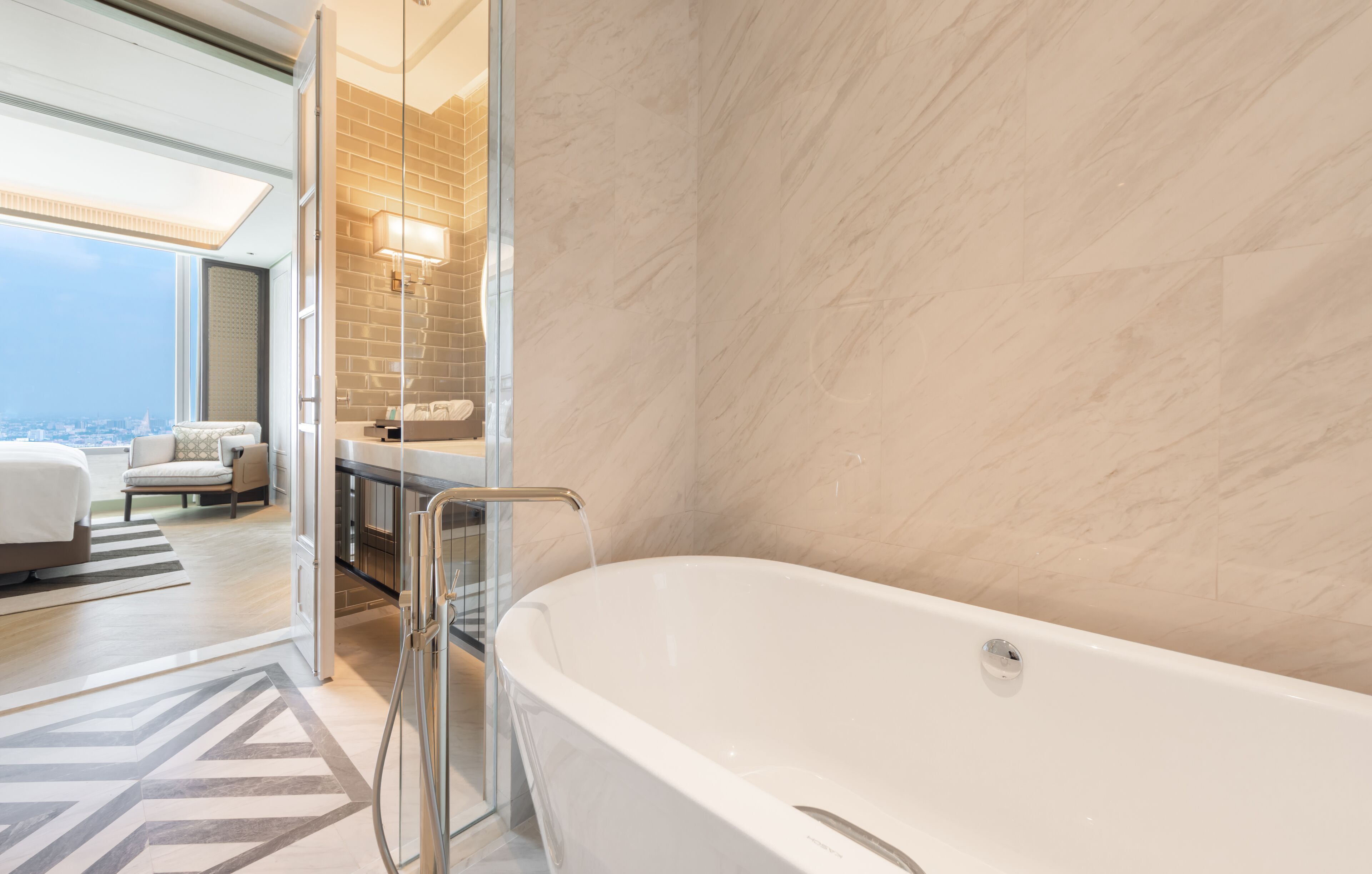 A modern bathroom with a freestanding bathtub, a glass shower enclosure, and a view of the city.