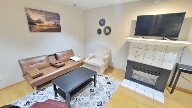 A living room with a sofa, armchair, coffee table, fireplace, TV, and decorative wall art.