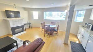 A modern living room with a fireplace, a TV, a dining table with chairs, and a sofa.