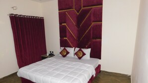 A hotel room with a large bed, a wooden floor, and a red curtain. - Empire Hotel (Lahore)