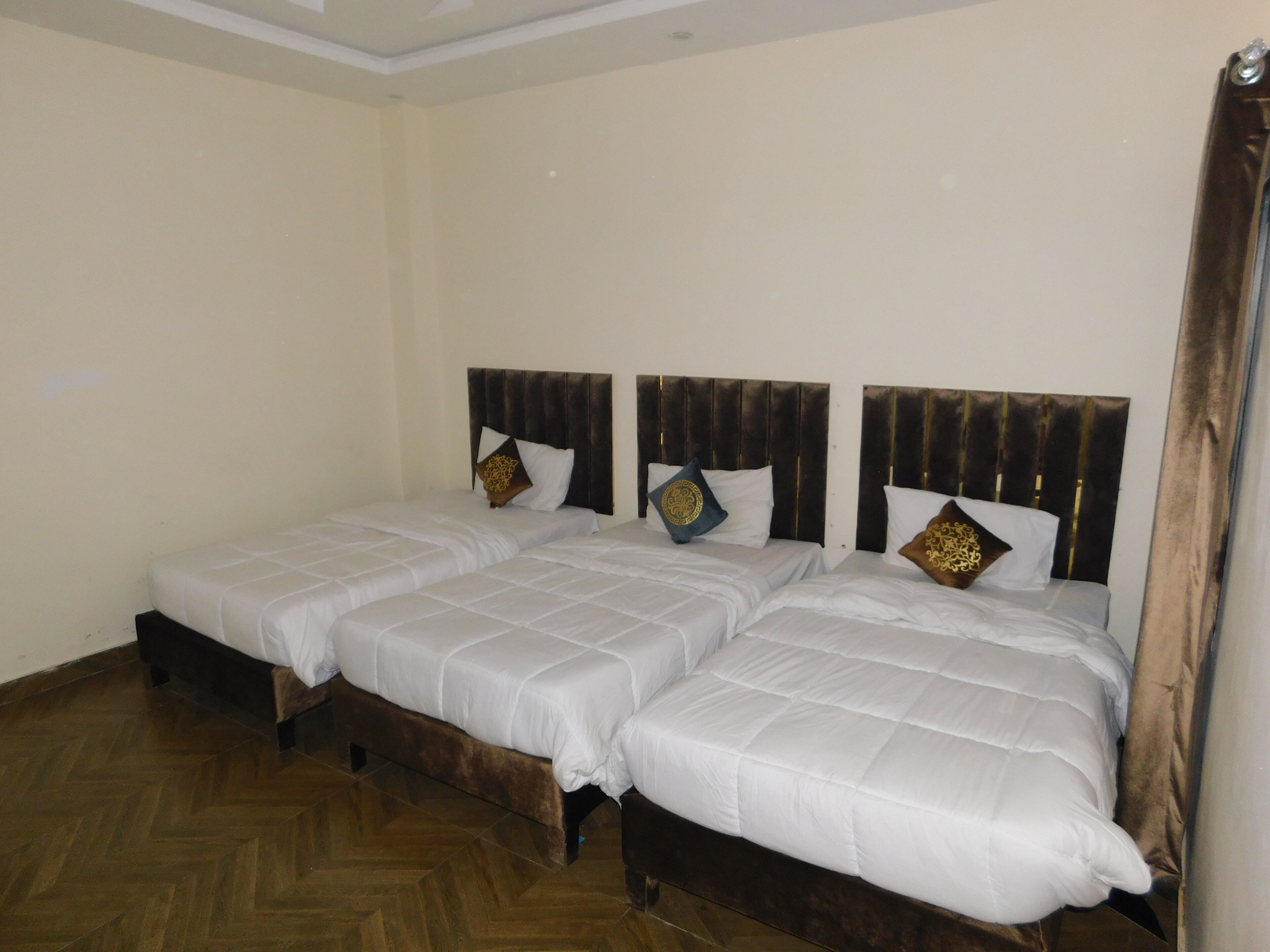 A double room with two beds, wooden headboards, and a herringbone-patterned floor.