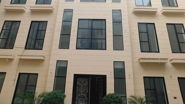 A multi-story building with a beige facade, large windows, and a central entrance with decorative doors. - Empire Hotel (Lahore)