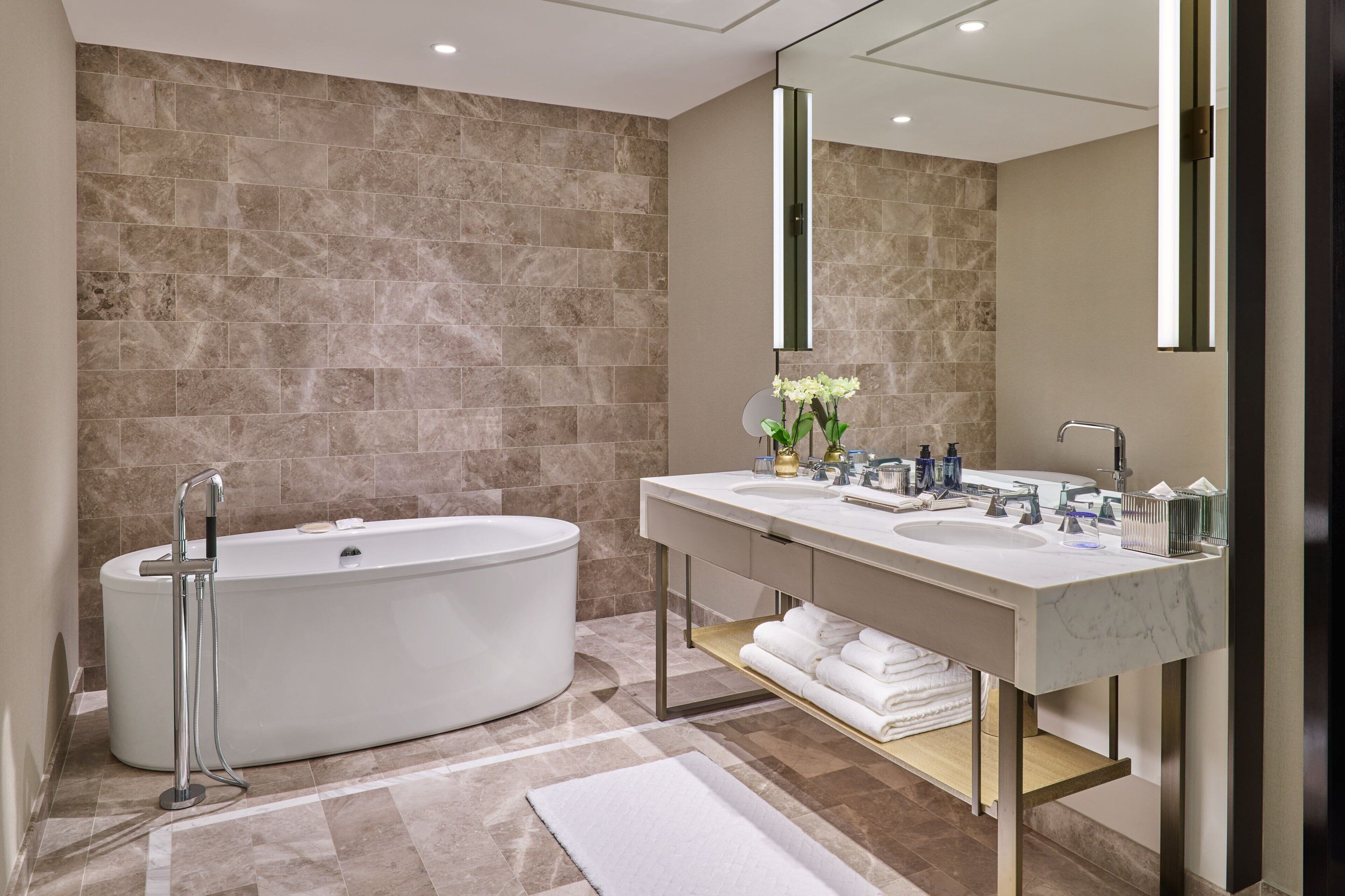 A modern bathroom with a freestanding bathtub, a double sink vanity, and a large mirror.