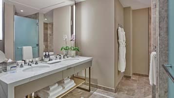 A modern bathroom with a dual sink vanity, a large mirror, and a shower area.