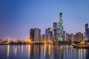 Une vue sur les gratte-ciel d’une ville au crépuscule, leurs façades se reflétant dans l’eau.