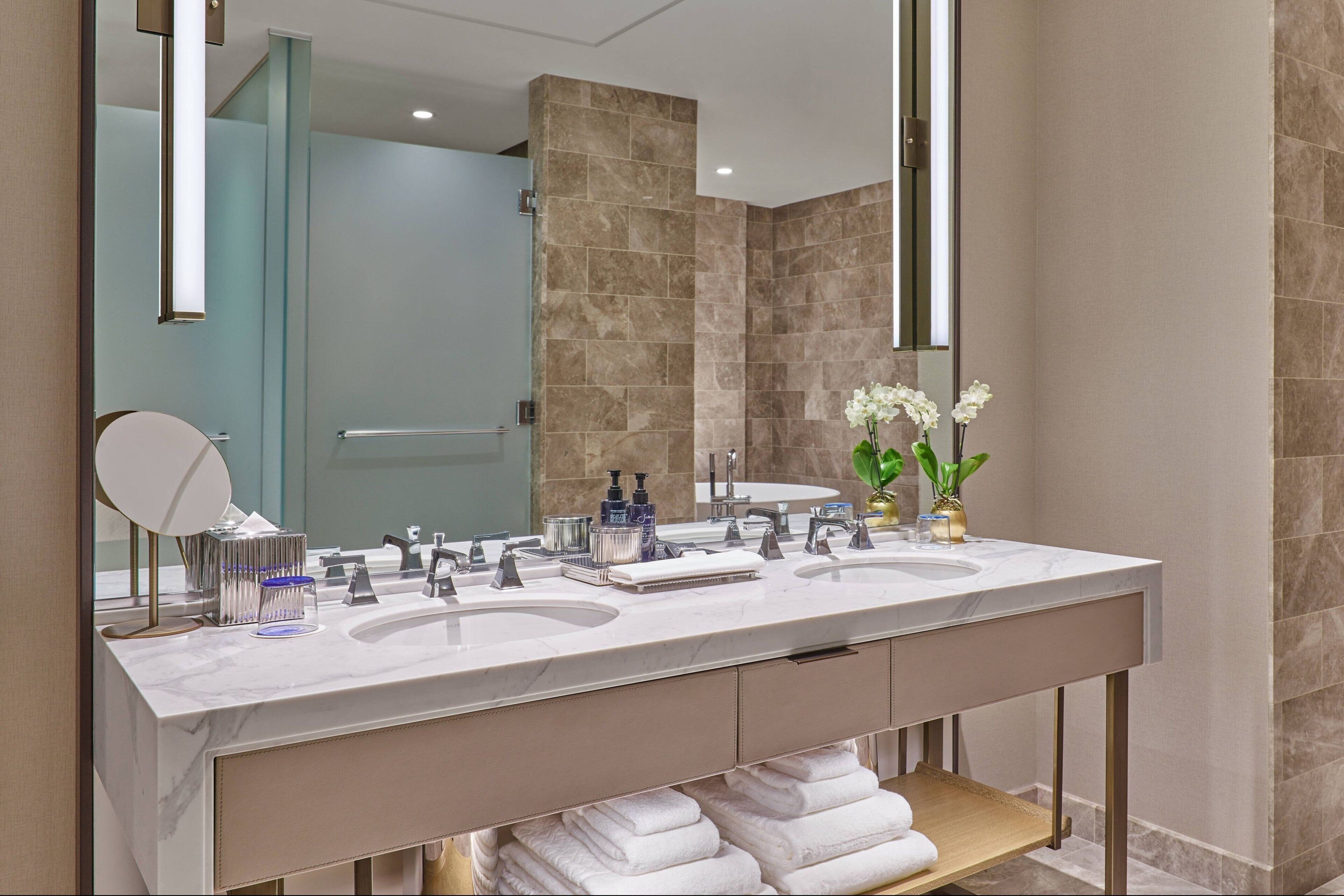 A modern bathroom with two sinks, a large mirror, and a towel rack.