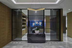 Un intérieur moderne avec une table noire au centre, des stores verticaux et un fond éclairé en bleu.