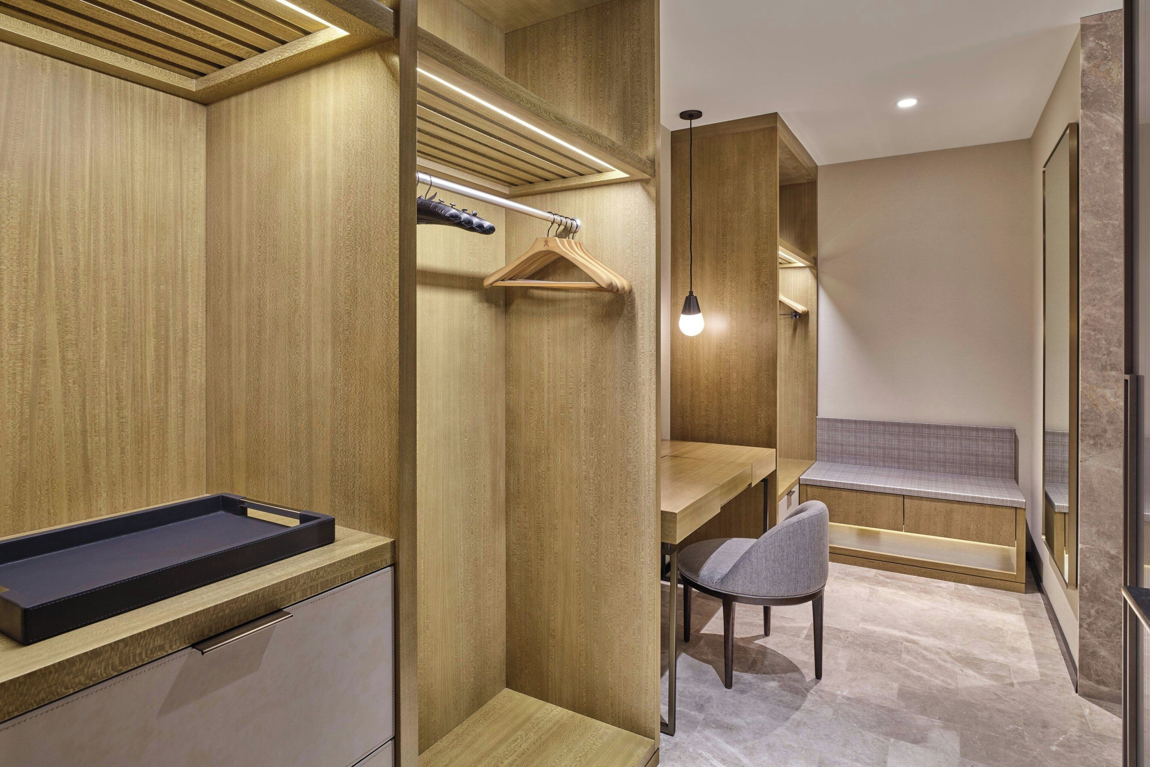 Une salle de bain moderne avec un meuble-lavabo en bois, une douche suspendue et un banc doté d’un luminaire.