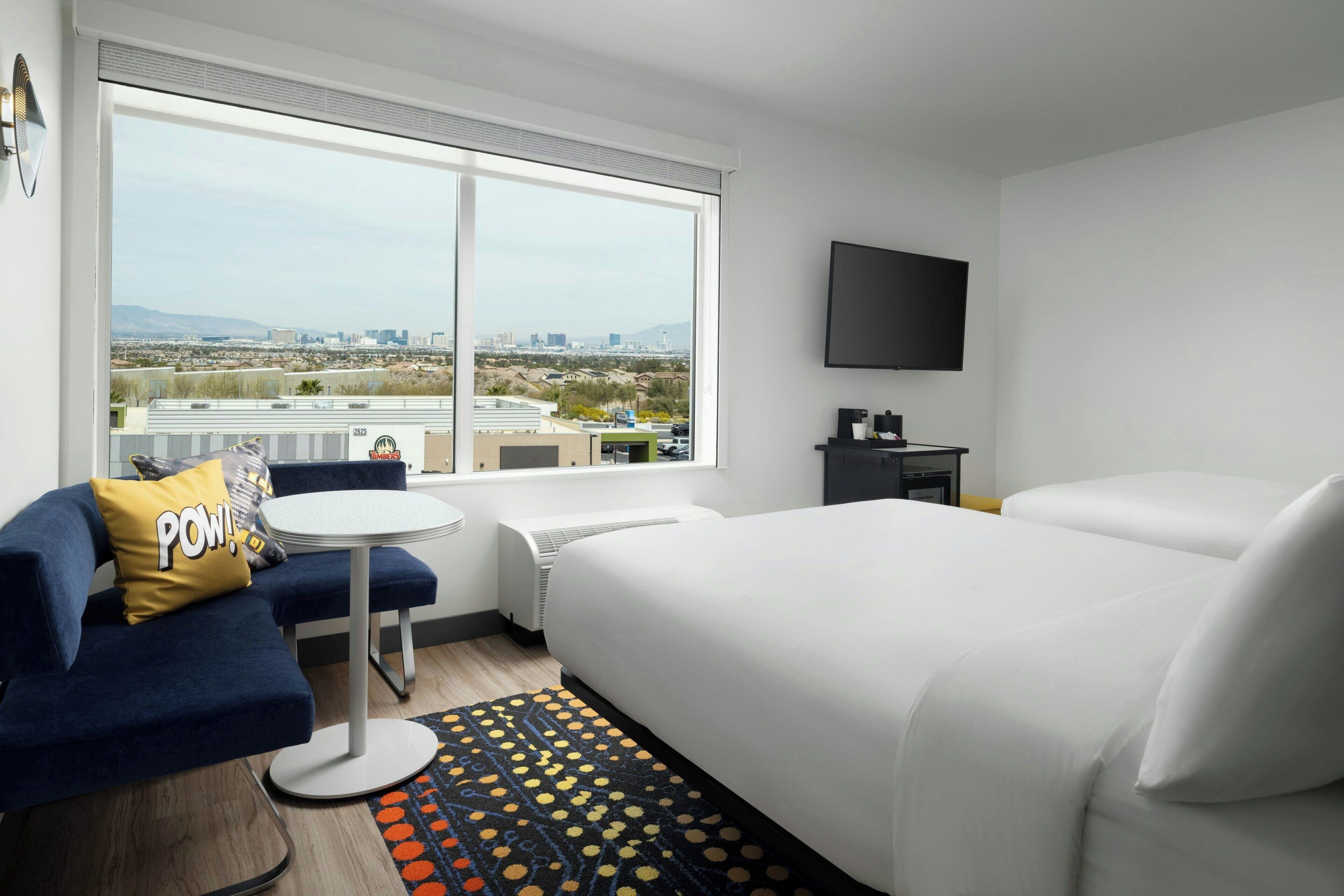 A hotel room with a large bed, a sofa, a small table, and a TV.