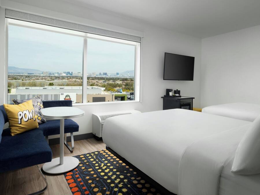 A hotel room with a large bed, a sofa, a small table, and a TV.
