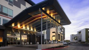 A modern hotel with a covered entrance, large windows, and a clear sky. - Aloft by Marriott Henderson (Henderson)