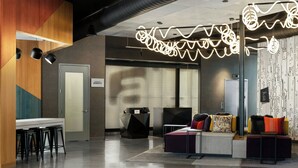 A modern lobby with a reception desk, seating area, and a patterned wall. - Aloft by Marriott Henderson (Henderson)